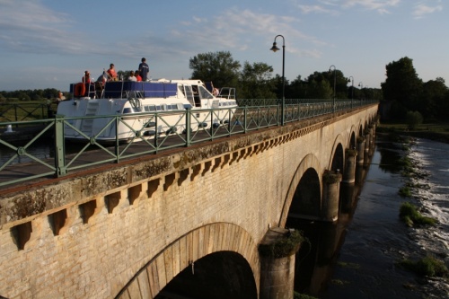 Photo d'un bateau de location sur un pont canal sur le canal du Nivernais lors d'une croisière fluviale